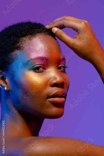 African american woman with short hair and colourful make up touching head