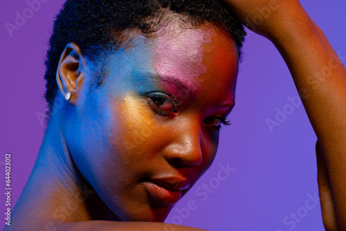 African american woman with short hair and colourful make up touching head