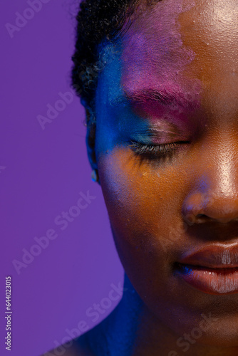 Half portrait of african american woman with short hair and colourful makeup with eyes closed