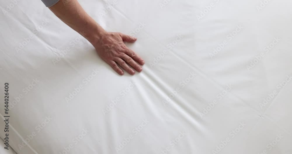 Man touches soft white mattress on bed closeup. Comfortable sleep and bed linen Man touches soft white mattress on bed closeup. Comfortable sleep and bed linen