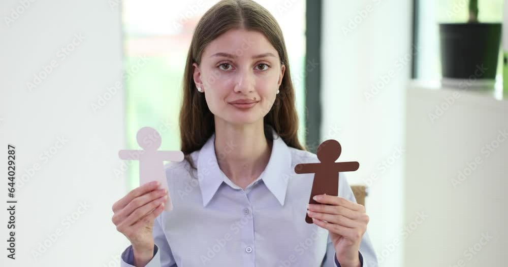 Woman holds paper cut figures of people as symbol of interracial relations. Interracial communication and racial attitudes Woman holds paper cut figures of people as symbol of interracial relations. Interracial communication and racial attitudes