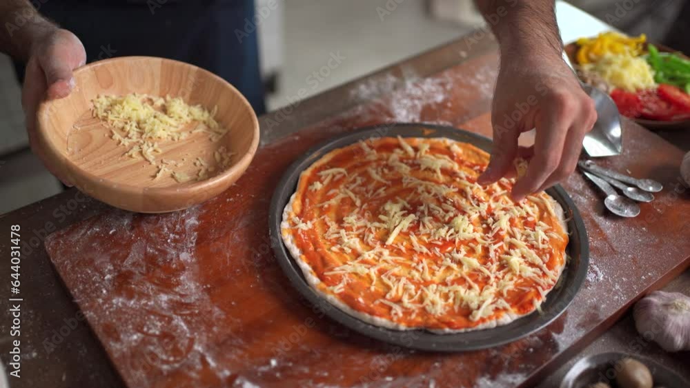 Happy cheerful caucasian man making - baking a pizza at home, man adding an ingredients over the pizza round in a tray before put it in the oven. Happy cheerful caucasian man making - baking a pizza at home, man adding an ingredients over the pizza round in a tray before put it in the oven.