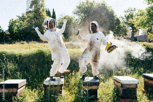 фотографія Joyful apiarist laughing and dancing during work in countryside