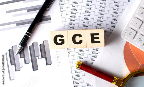 GCE text on wooden block on graph background with pen and magnifier photo