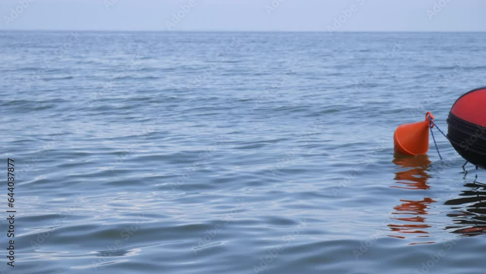 Marine orange buoy drifts next to a lifeboat in the sea. Marine orange buoy drifts next to a lifeboat in the sea.