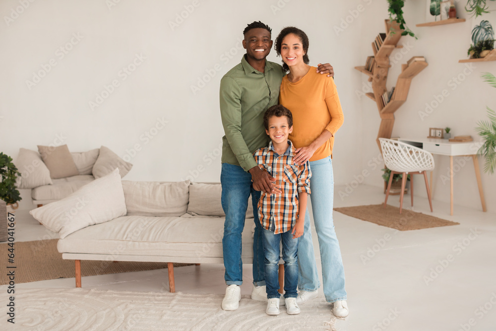 Smiling Multiracial Parents Hugging Their Little Son Standing At Home Smiling Multiracial Parents Hugging Their Little Son Standing At Home
