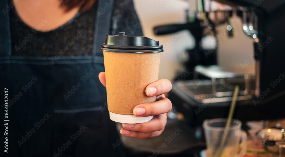 Close-up of hand Barista is holding in hands hot coffee in a takeaway paper cup. Coffee take away at cafe shop, Startup successful small business concept