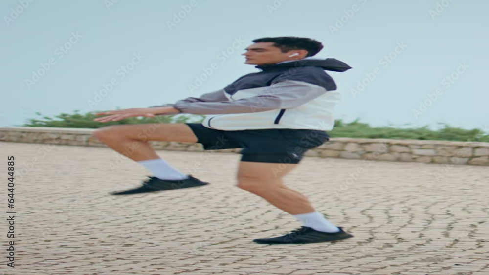 Athlete doing high knees exercise vertical. Focused sportsman warming up jumping Athlete doing high knees exercise vertical. Focused sportsman warming up jumping