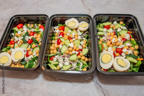 Meal prep protean salad with chick peas, cucumbers, egg and tomatoes. Healthy food prepping. 