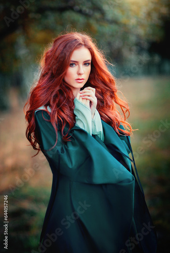 Portrait of  a beautiful red haired girl in green medieval dress on glowing sun. Fairy tale story about brave heart woman.Amazing model looking at camera.Warm art work
