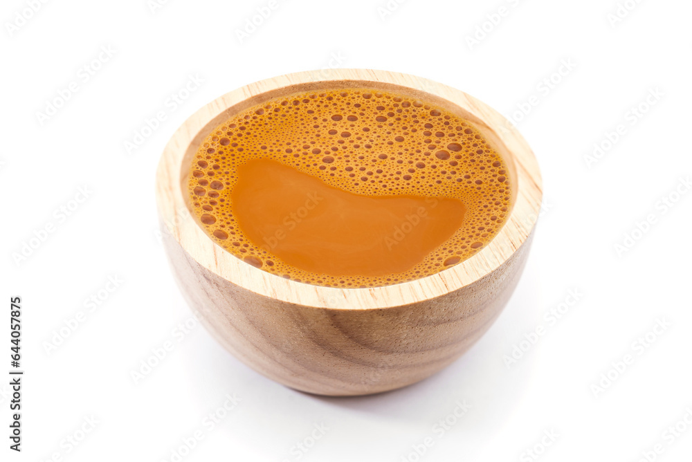 Hot milk tea in a wooden cup on white Hot milk tea in a wooden cup on white