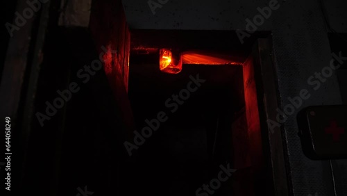 Close-up of a rotating red emergency siren lamp on the wall of a dark tunnel. A bomb shelter, an emergency signal on the wall during an air raid. photo