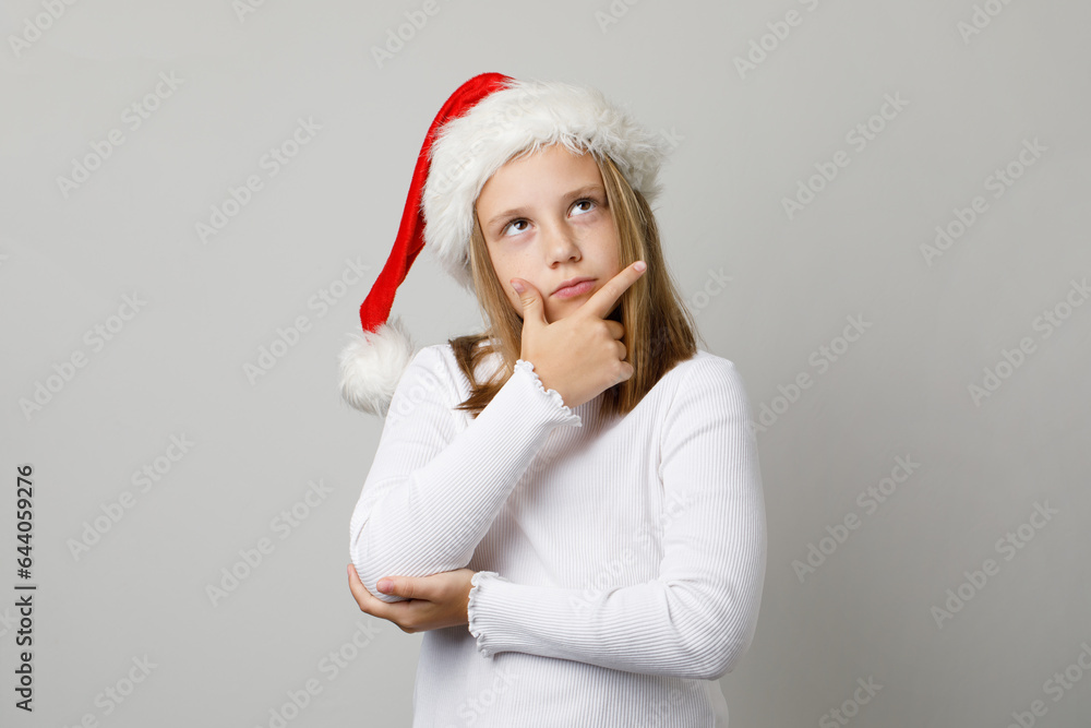 Christmas child girl in Santa hat thinking on white background Christmas child girl in Santa hat thinking on white background