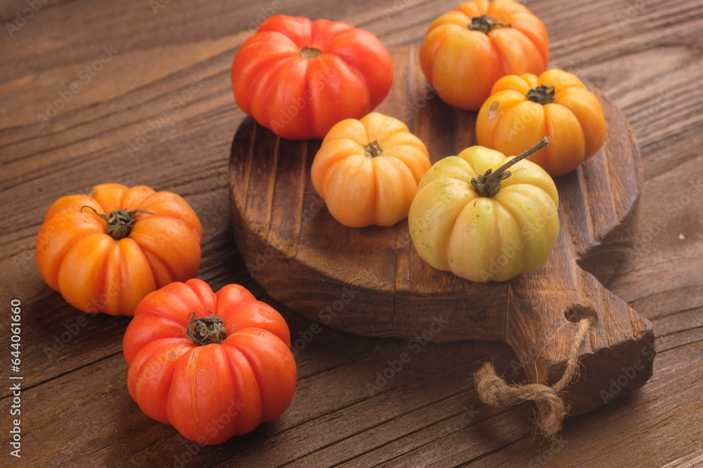 Ranti tomatoes or Mawar tomatoes (Lycopersicum esculentum var. commune Bailey) on a brown wooden table Ranti tomatoes or Mawar tomatoes (Lycopersicum esculentum var. commune Bailey) on a brown wooden table