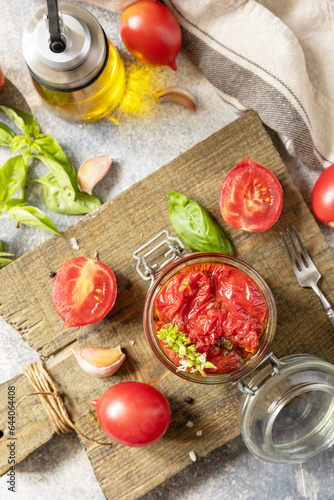 Sun-dried tomatoes in jar with spices and herbs. Healthy homemade fermented food. Home economics, autumn harvest preservation. View from above.
