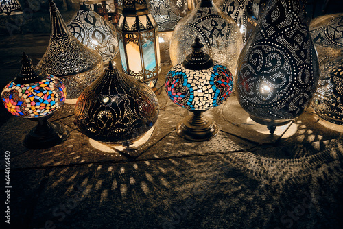 Glowing arabic lamps for sale stand in front of egyptian souvenir shop casting quaint shadows. Traditional middle eastern lanterns. Khan El Khalili market, Cairo, Egypt photo