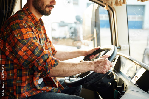 Side view, sitting inside the vehicle. Young truck driver in casual clothes © standret