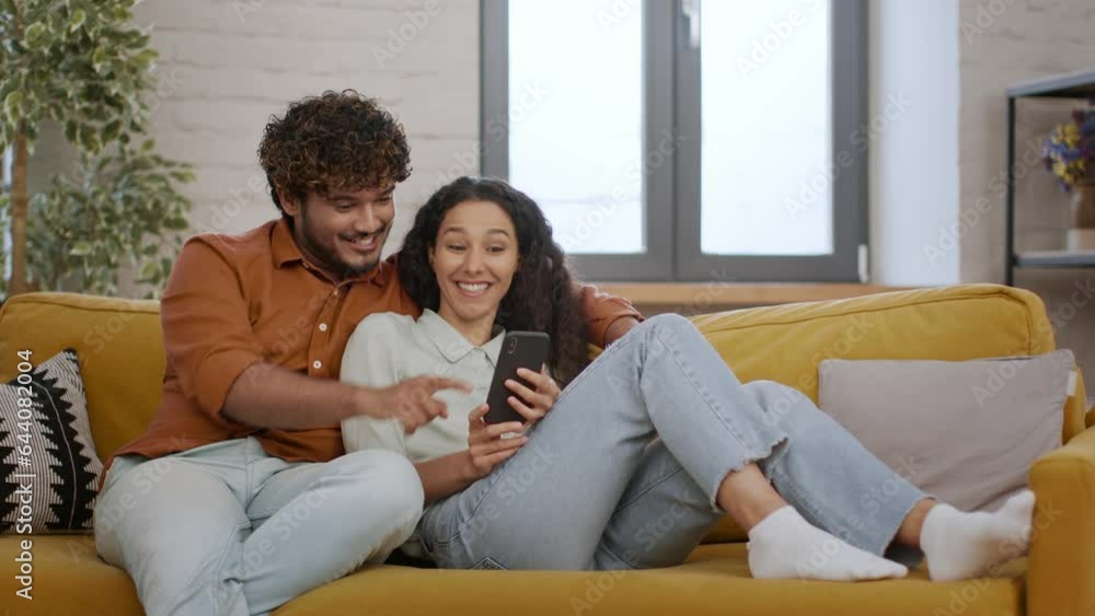 Young positive middle eastern man and woman spouses shopping online on smartphone, looking at mobile app, free space Young positive middle eastern man and woman spouses shopping online on smartphone, looking at mobile app, free space