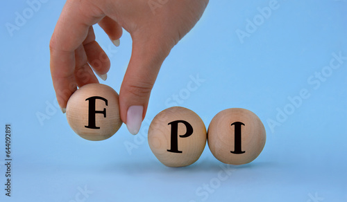 A woman's hand holds a wooden ball with the abbreviation FPI . photo