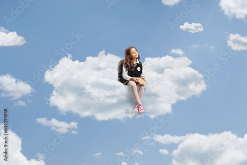 Schoolgirl sitting on a cloud up in the sky