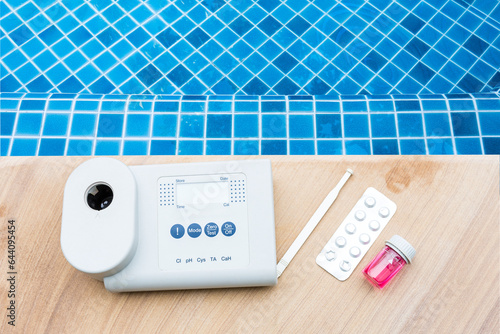 Quality water analysis tool on swimming pool edge with space on water background, measure chlorine and pH, pH testing with water photometer and reagent table photo