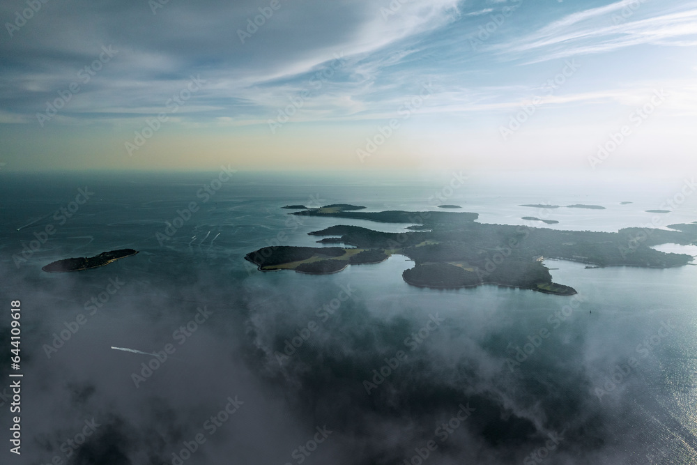 Aerial view of Brijuni National Park, a group of islands along the Adriatic Sea coastline with a misty fog at sunset near Pula, Istria, Croatia. Aerial view of Brijuni National Park, a group of islands along the Adriatic Sea coastline with a misty fog at sunset near Pula, Istria, Croatia.