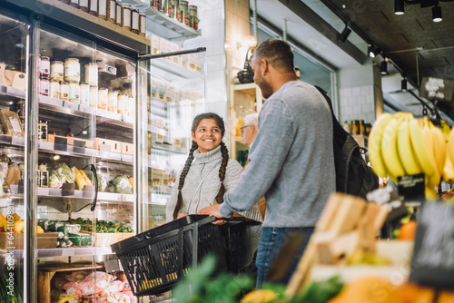 Smiling girl shopping for grocery with father at delicatessen photo