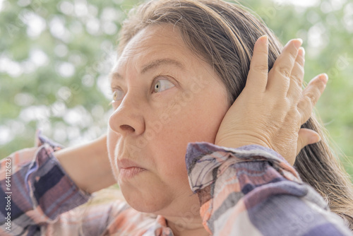 Bilde på lerret mature caucasian woman 50 years holding hand to sore ears, close up female face