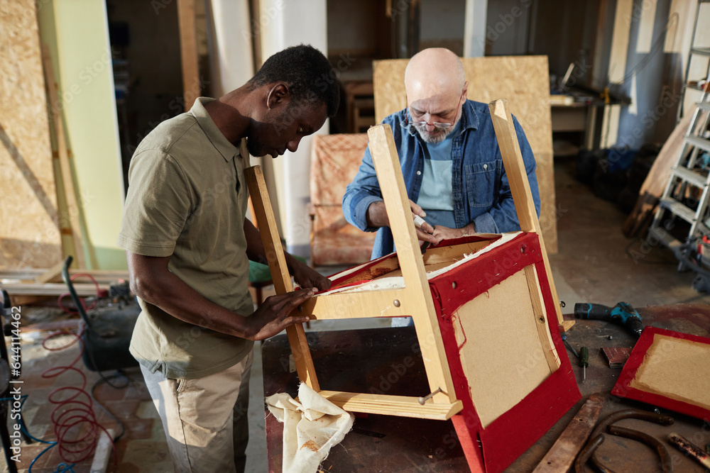 Portrait of two people repairing old furniture while working in carpentry workshop together, copy space Portrait of two people repairing old furniture while working in carpentry workshop together, copy space