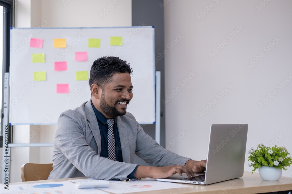 Young handsome happy man working in office on laptop and smiling Young handsome happy man working in office on laptop and smiling