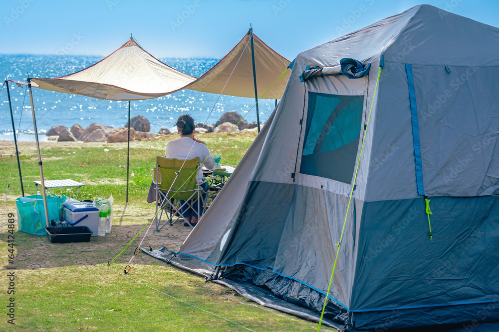 Camping tent and activity on field near the beach. Tent camping area for tourists on lawn near the beach. Holiday outdoor activities with travel and camping at seaside. Happiness outdoor recreation.