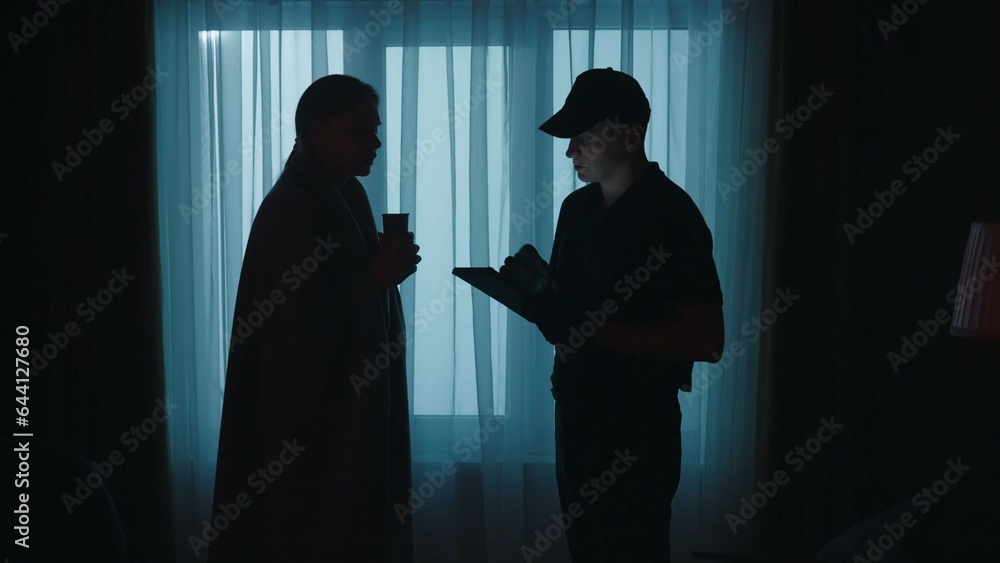 Young shocked woman in blanket talking with policeman. Crime scene creative concept.