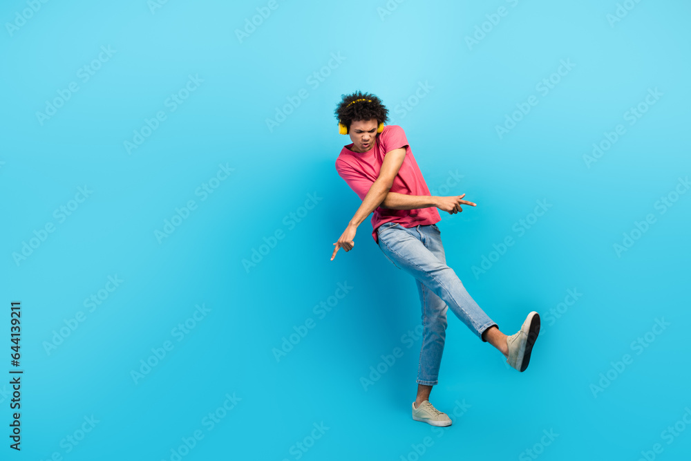 Full size photo of attractive young man cool dance crossed hands earphones dressed stylish pink clothes isolated on blue color background