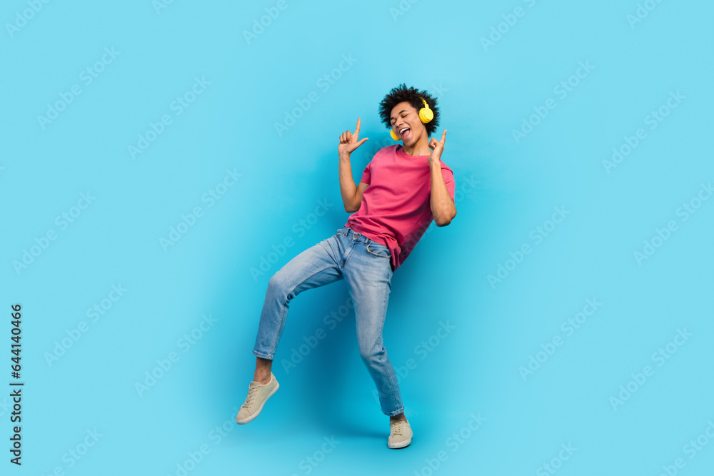 Full size photo of attractive young man raise fingers up dancing earphones dressed stylish pink clothes isolated on blue color background