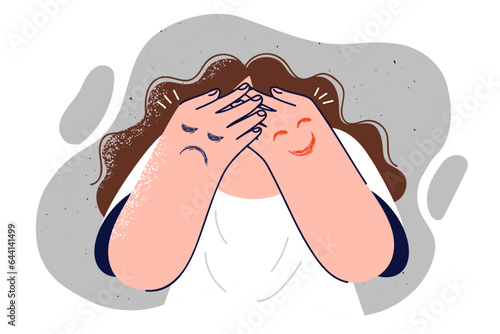 Woman wants to hide emotions by covering face with hands with positive and negative emoticon