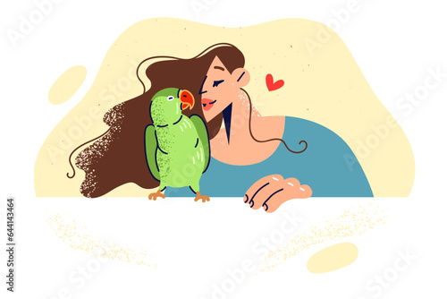 Woman kisses green parrot, rejoicing at presence of beloved pet and enjoying communication with bird