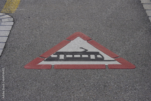Traffic sign for tram crossing ahead painted on the ground.  The caution traffic sign warns from the potential danger of the tram passage. Sign angle view with some copy space. © Lucia