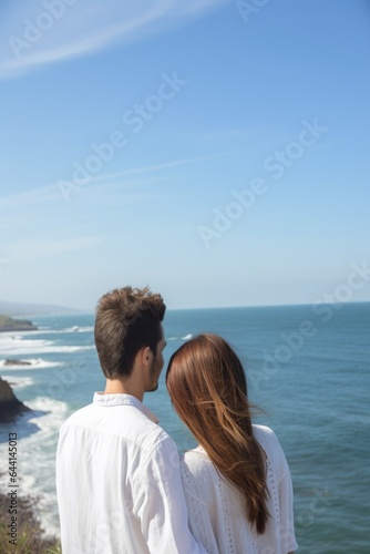 rearview shot of a happy young couple overlooking the ocean
