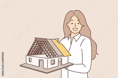 Woman architect holds model of house, demonstrating engineering solution for construction buildings