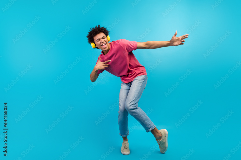 Full length photo of nice young guy yellow headphones singing song dressed stylish pink garment isolated on blue color background