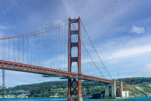 San Francisco, CA, USA - July 13, 2023: Golden Gate bridge south landing , ocean side, with 1 tower under blue cloudscape. Green hills and city on horizon