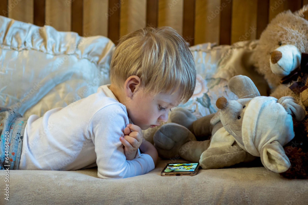 boy, child, kid, internet, smartphone, bed, sitting, nursery, children playing, toys, child development, tablet, computer, one, European, Georgian, blond boy, child, kid, internet, smartphone, bed, sitting, nursery, children playing, toys, child development, tablet, computer, one, European, Georgian, blond