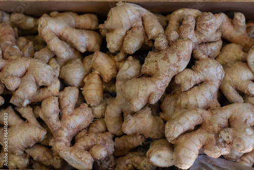 Fresh ginger root in wooden box at market store.