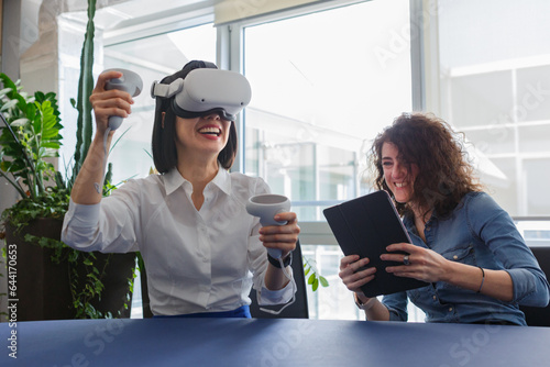 Canvas Print two women sitting at the table in the office and working with virtual reality vi