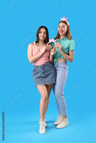 Female friends with crowns on blue background