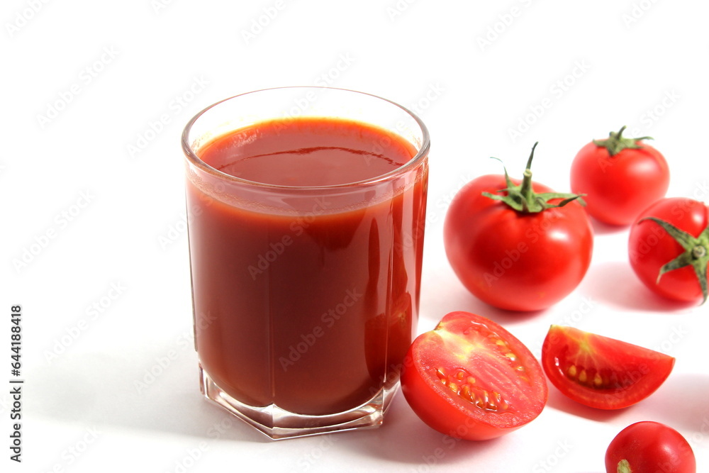 On a white background is a glass of tomato juice with tomatoes and herbs. On a white background is a glass of tomato juice with tomatoes and herbs.