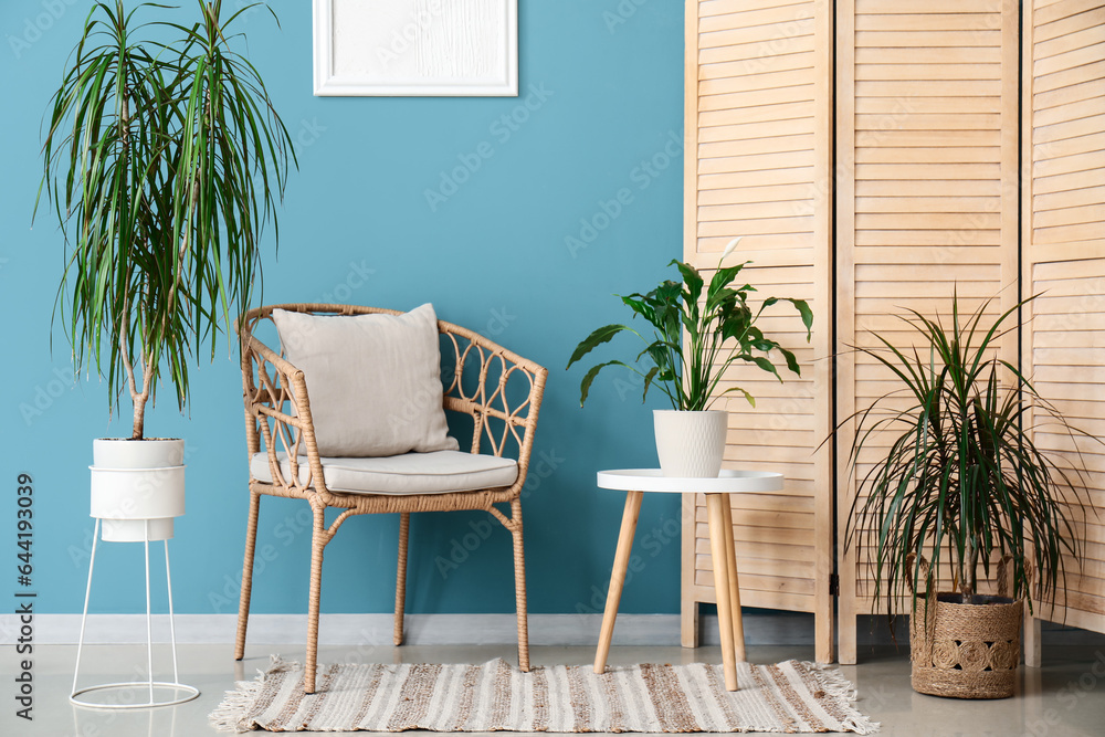 Interior of living room with houseplants, armchair and table