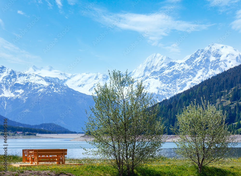 Reschensee ( or Lake Reschen) summer landscape with blossoming meadow picnic wooden bench near (Italy) Reschensee ( or Lake Reschen) summer landscape with blossoming meadow picnic wooden bench near (Italy)