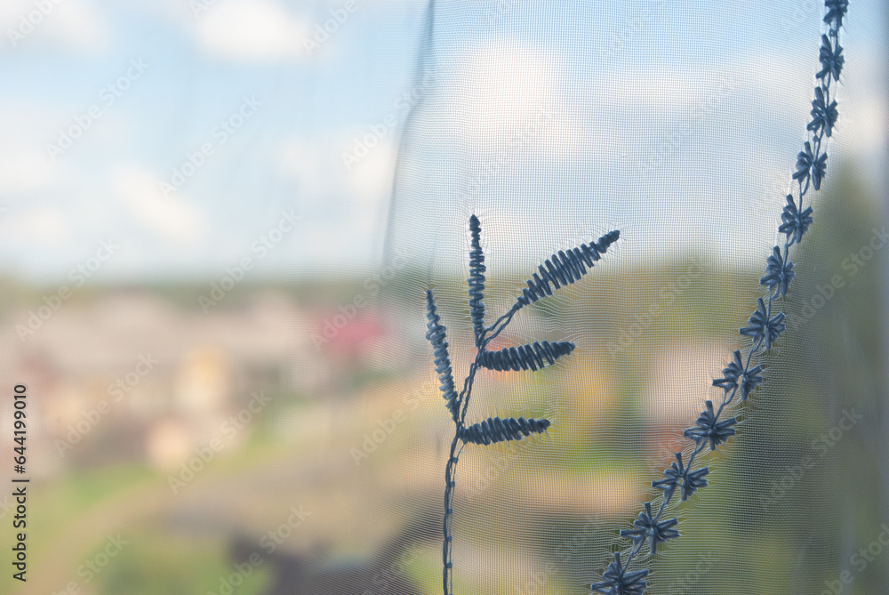 Photo of a red tulle on a window with a thread pattern