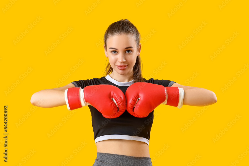Sporty young woman with boxing gloves on yellow background Sporty young woman with boxing gloves on yellow background